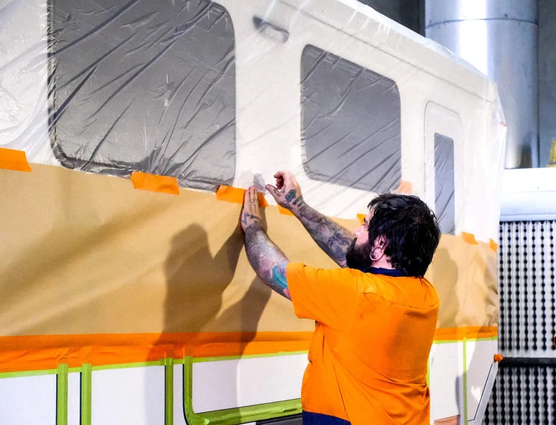 A Vision RV worker masking a caravan's exterior for finishing on the factory floor